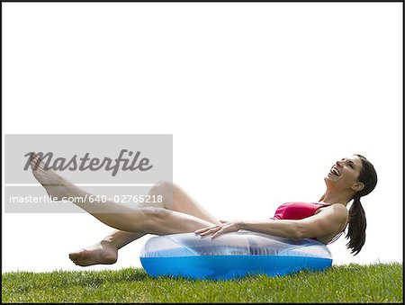 Woman in bikini lying in swimming ring on grass smiling