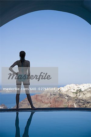 Frau im Badeanzug stehen am Rand des hinteren unendlich mit Poolblick