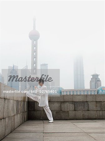 Man doing tai chi outdoors with city skyline in background
