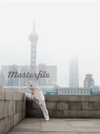 Man doing tai chi outdoors with city skyline in background