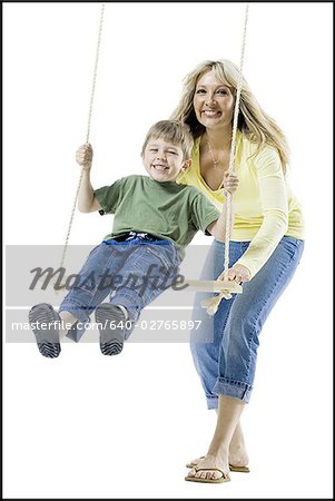 Mother pushing her son on a swing