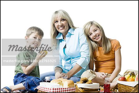 Porträt einer Mutter und ihren beiden Kindern, die mit einem Picknick