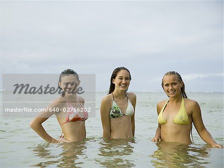 Three teenage girls standing in the sea and laughing