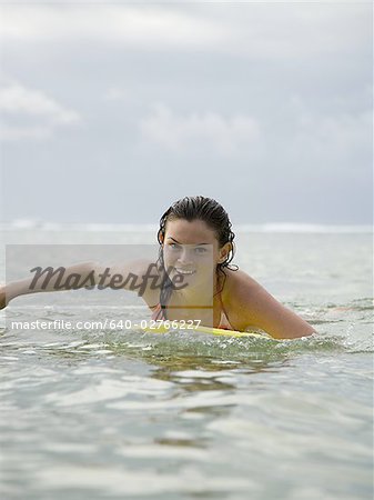 Portrait d'une jeune adolescente flottant sur une planche de surf dans la mer