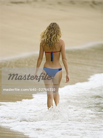 Rear view of a young woman walking on the beach