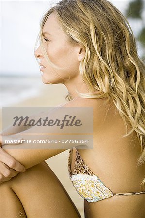 Profil d'une jeune femme assise sur la plage