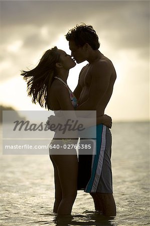 Junges Paar küssen bei Sonnenuntergang im Meer