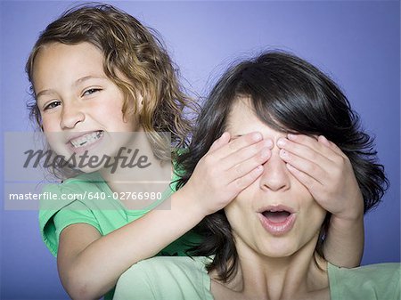 Close-up of a girl covering her mother's eyes