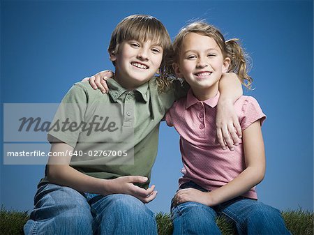 Portrait of a boy sitting with his arm around his sister