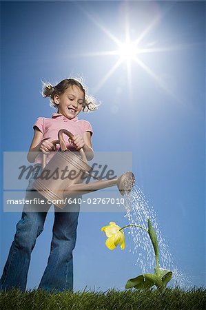 Low angle view of a girl watering a plant
