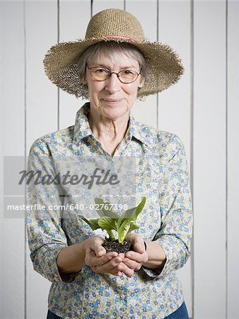 Portrait of an elderly woman holding a plant