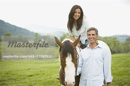 Frau mit einem Mann neben ihr auf einem Pferd sitzend