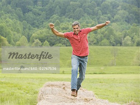 Portrait d'un homme saute sur une balle de foin