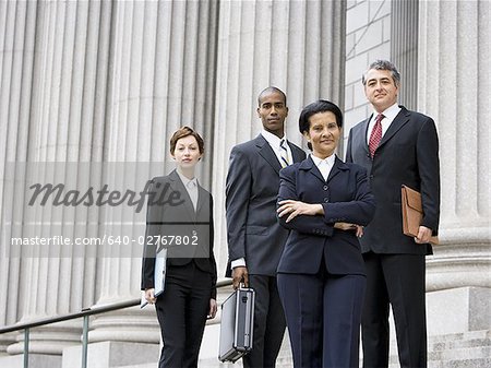 Portrait d'avocats souriant devant un palais de justice