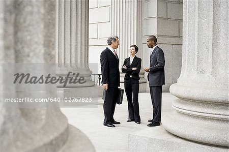 Drei Anwälte sprechen vor einem Gerichtsgebäude