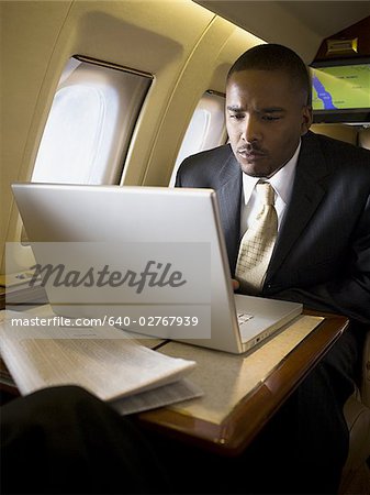 Businessman using a laptop in an airplane