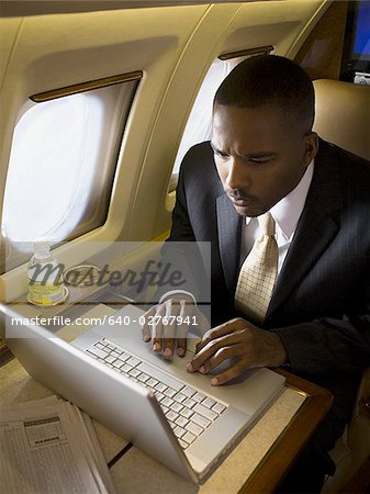 Kaufmann mit einem Laptop in einem Flugzeug