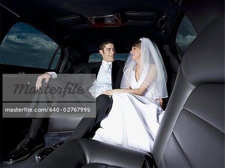 Close-up of a newlywed couple sitting in a car and looking at each other