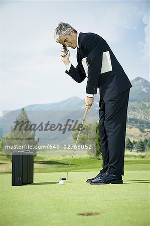 Profile of a businessman playing golf and talking on a mobile phone