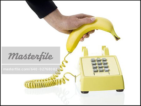 Gros plan de la main d'une personne ramasser un récepteur téléphonique de banane