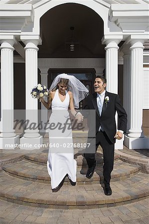 Couple de jeunes mariés en descendant les marches devant un immeuble
