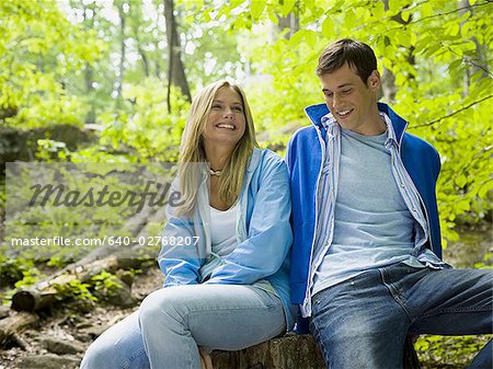 Close-up of a young couple sitting in the forest and smiling