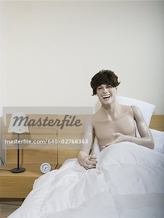 Male mannequin sitting on the bed and laughing