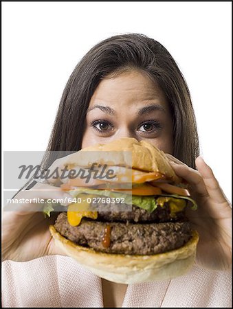 Gros plan d'une jeune femme tenant un hamburger