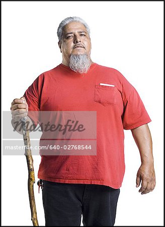 Homme de corpulence plus âgé avec une barbe longue grise tenant une canne