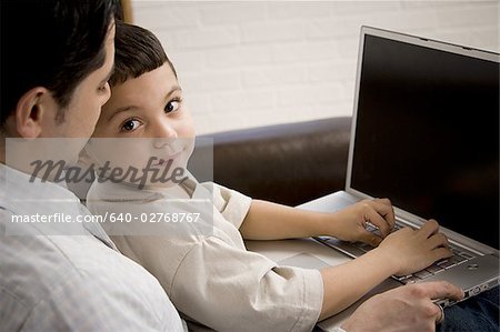 Father and young son working on laptop computer