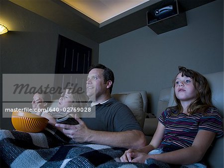 Father and daughters watching movie in home theater