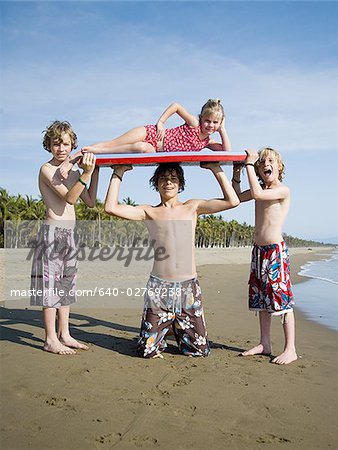 Drei jungen und Schwester spielen am Strand
