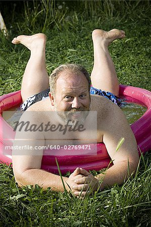 Overweight man in inflatable wading pool