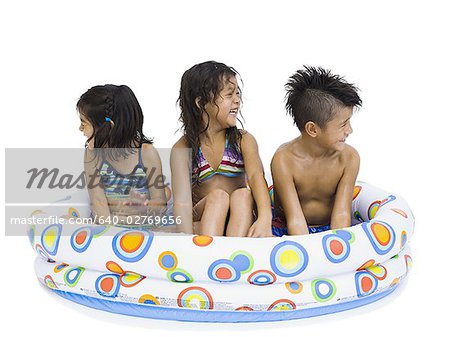 Three young children playing in inflatable pool