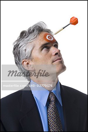 Man with bull's-eye on forehead and dart coming toward him