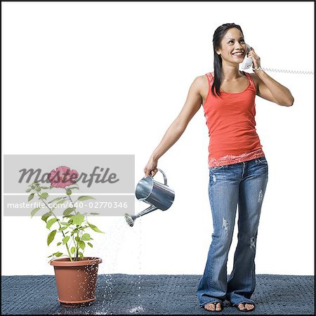 Distraite femme arrosant les fleurs, mais manque de pot