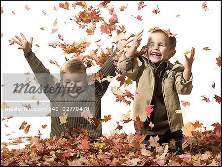Young children playing in pile of fallen leaves