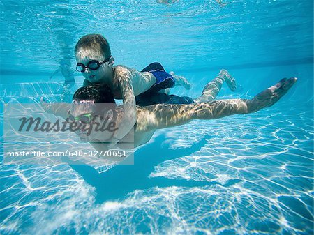 Father and son swimming underwater in pool