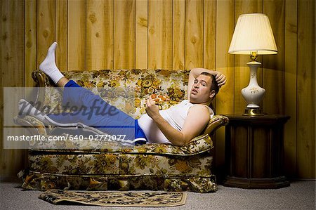 Man on sofa with pizza and TV remote