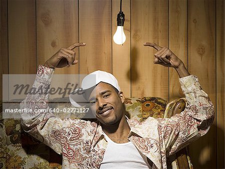 Homme assis sur un canapé sous ampoule pointant vers le haut