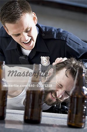 Police officer arresting man lying down with beer bottles