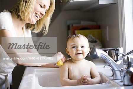 Woman bathing baby in sink