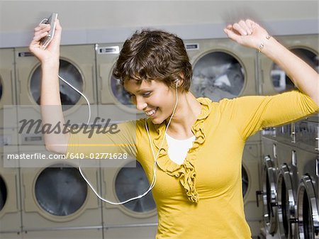 Woman with mp3 player in Laundromat dancing