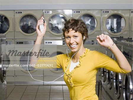 Woman with mp3 player in Laundromat dancing