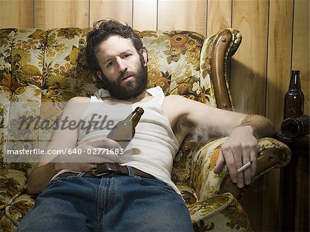 Man on couch with beer bottle and cigarette