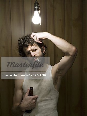 Man standing under light bulb with cigarette and beer bottle