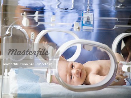Baby in incubator with man in uniform