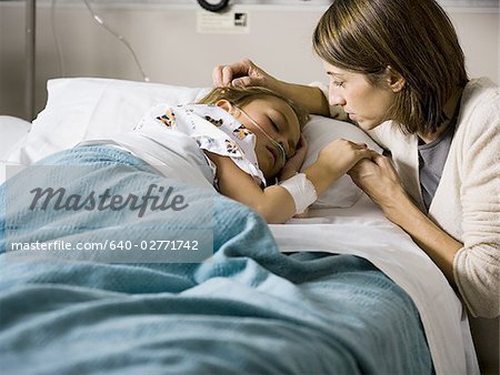 Woman holding hands with young girl in hospital