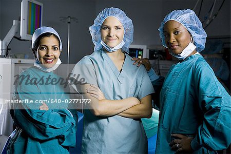 Three women in scrubs with arms crossed smiling