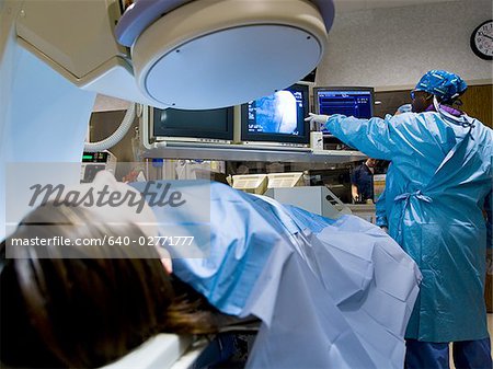 Woman on diagnostic bed with male and female technicians looking at monitors